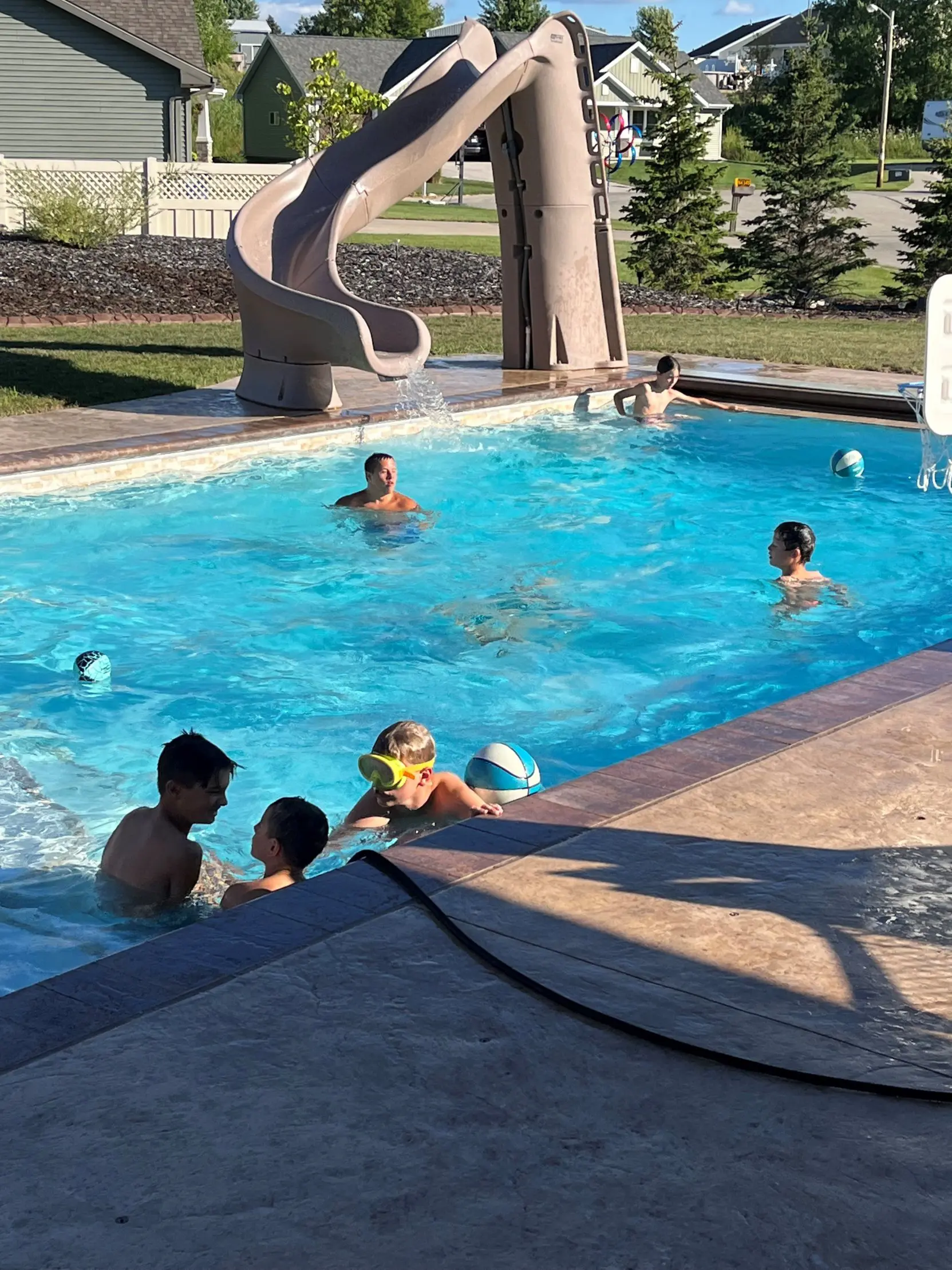 Kids swimming in a pool with a slide