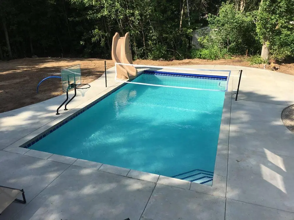 pool with slide, volleyball net, and basketball hoop